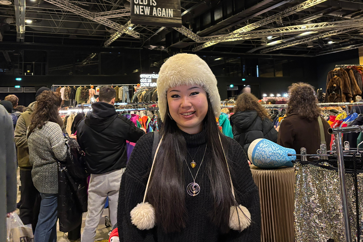 Ragazza con colbacco di pelliccia bianca e maglione nero tra gli stand dell East Market di Milano